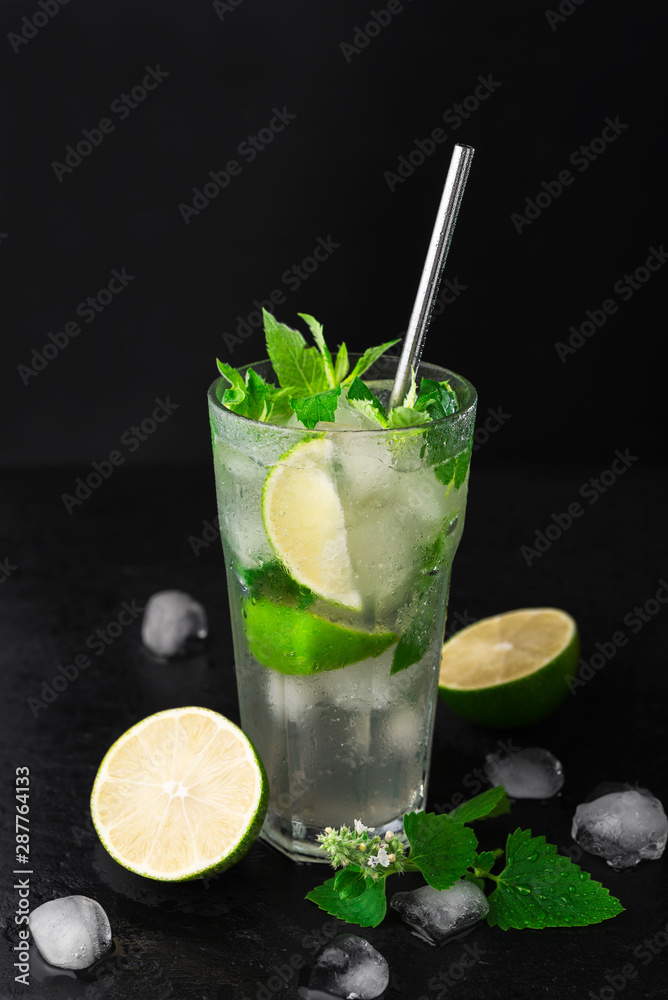 Fototapeta premium Cocktail Mojito with ice in a glass, lime, leaf mint and metal straw