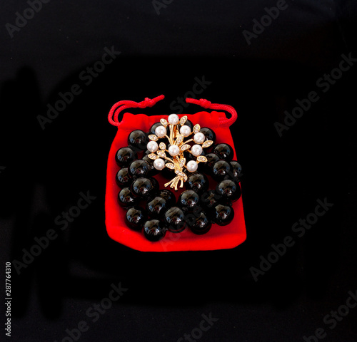 Black pearls and brooch on a white background
