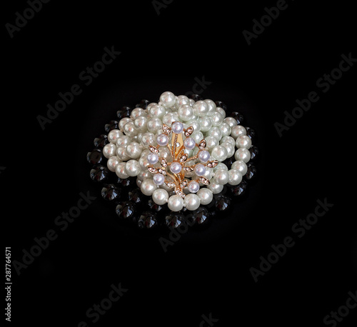 Black pearls and brooch on a white background