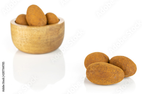 Group of six whole sweet brown chocolate cinnamon almond in tiny wooden bowl isolated on white background