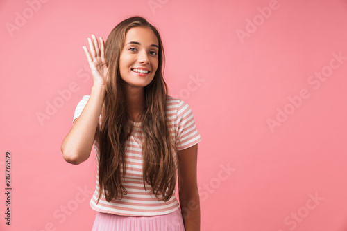 Cheery young pleased girl posing isolated over pink wall background try to hear you. photo