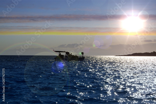 Sea and boat with sun in background