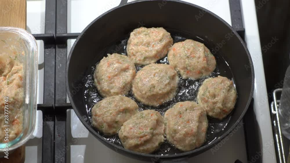 Elderly woman making pan fried chicken cutlets in cast iron frying skillet with oil on gas stove top view. Elderly woman making pan fried chicken cutlets in cast iron frying skillet with oil on gas stove top view.