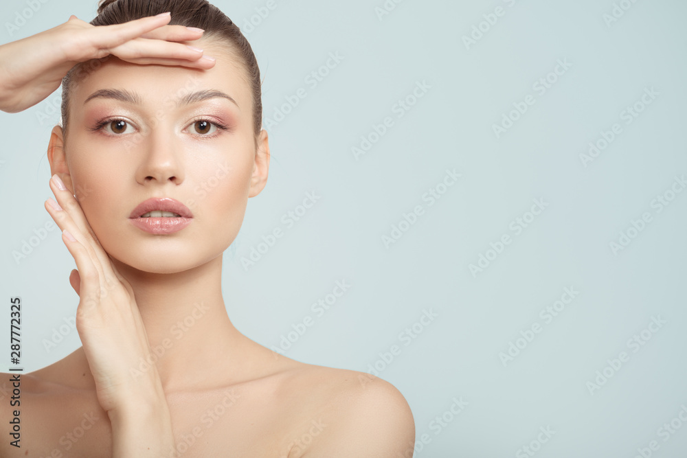 Naklejka premium woman with clean skin touches her cheeks with her hand. face skin concept on a blue background. close-up portrait