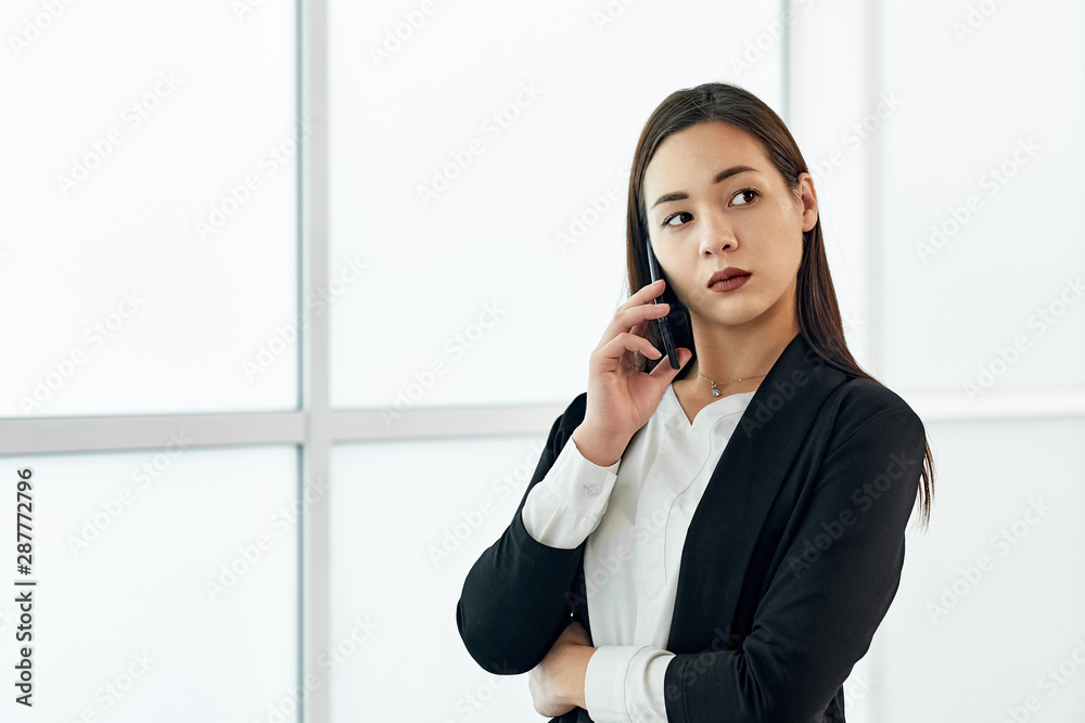 Asian Business woman talking on the phone. Portrait of beautiful girl in office on white background Asian Business woman talking on the phone. Portrait of beautiful girl in office on white background