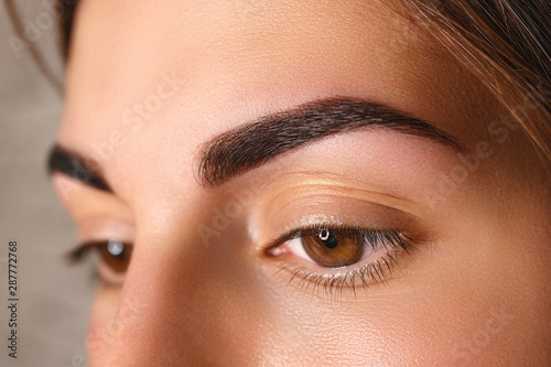 Young woman with beautiful eyebrows after correction, closeup photo