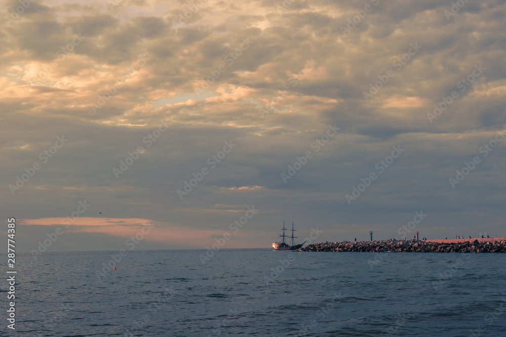 Port entrance during sunset under the cloudy sky.