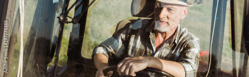 panoramic shot of self-employed farmer in straw hat driving tractor