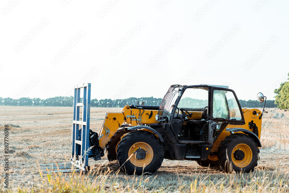 Obraz premium modern tractor on wheat field in country