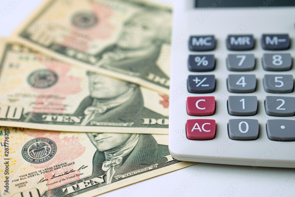 Calculator on ten dollars banknotes on a white background. Concept of Calculation of income and expenses Calculator on ten dollars banknotes on a white background. Concept of Calculation of income and expenses