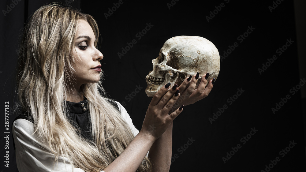 Naklejka premium Woman looking at skull on black background