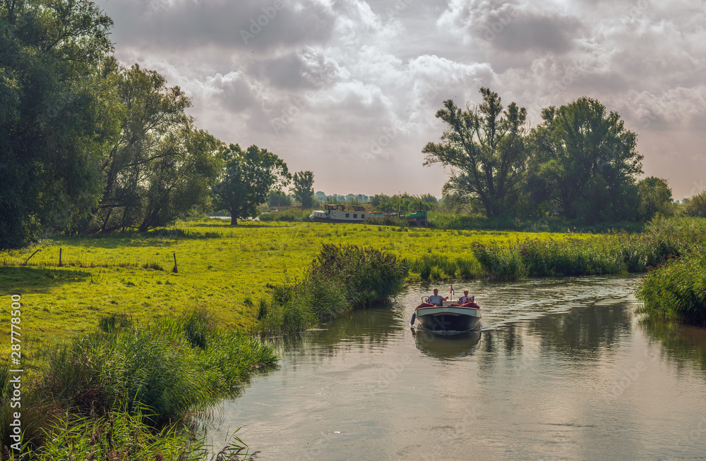 Two unrecognizable people sail through a stream with a sloop