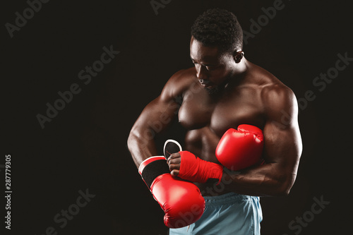 African muscular boxer wearing red gloves before fight