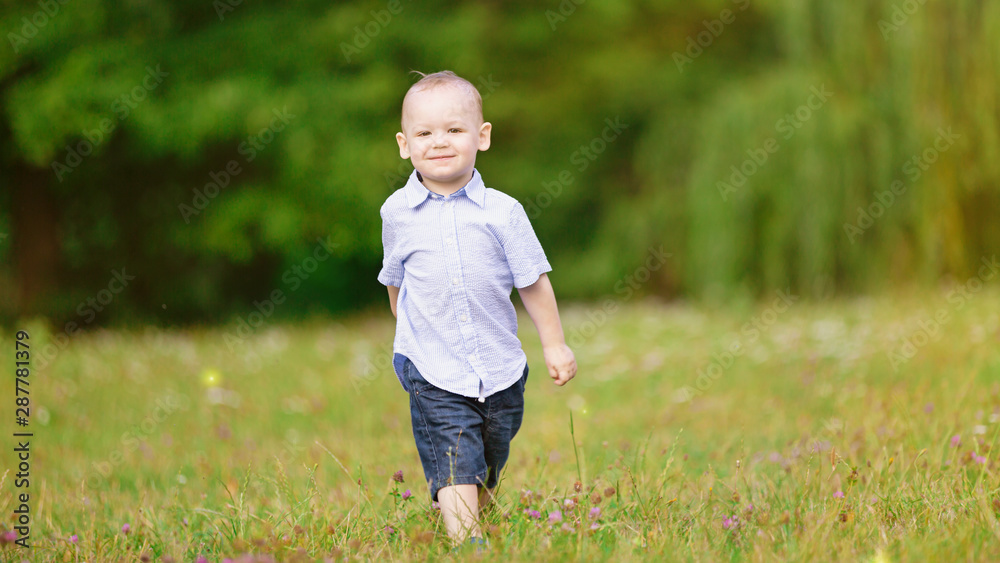 Little boy marching on the green grass in the park Little boy marching on the green grass in the park