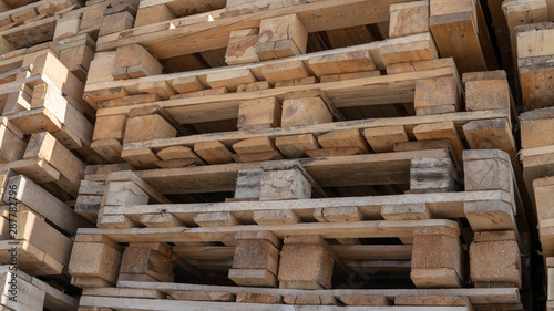 Wooden euro pallets for transfering goods to customers. Used wooden pallets in stack in the warehouse. Wooden pallet overlap.