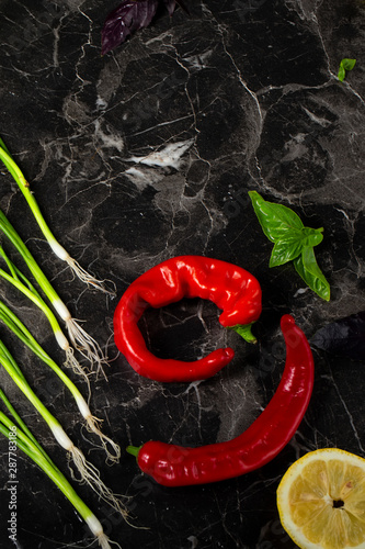 Vegetables for salad on a gray background. Red hot peppers and onions, lemon vertically. Still life of bright vegetables photo