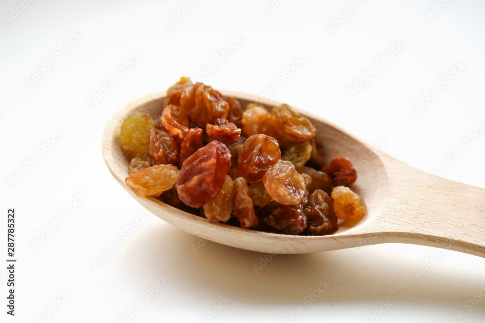 White grape raisins in a wooden spoon. sabza. on a white background.. White grape raisins in a wooden spoon. sabza. on a white background..