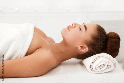 Beautiful young woman relaxing in light spa salon