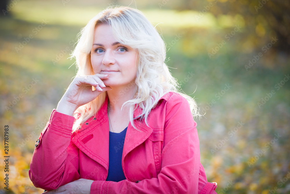 Beautiful middle-aged woman on the street. Plain blonde on autumn background Beautiful middle-aged woman on the street. Plain blonde on autumn background