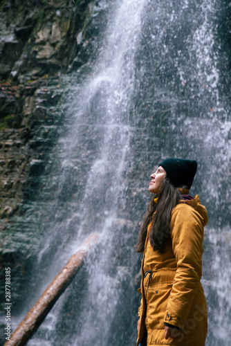 woman near waterfall in forest autumn season