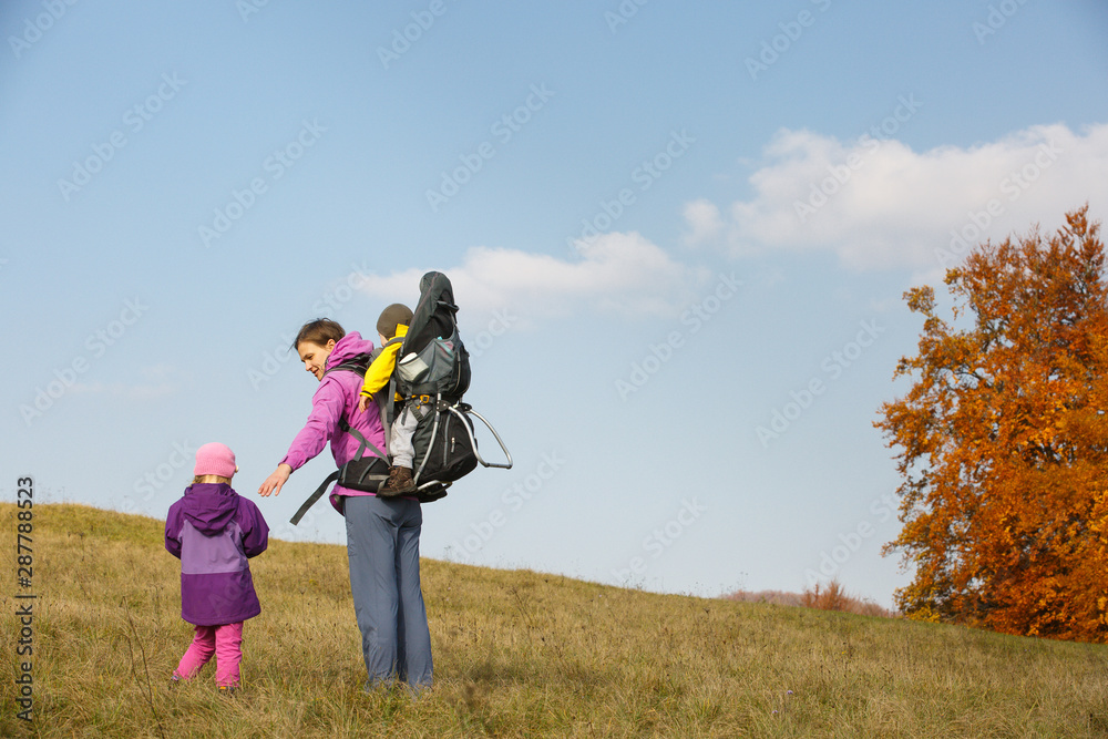 Mother with children hiking on a nice autumn day carrying kid Mother with children hiking on a nice autumn day carrying kid