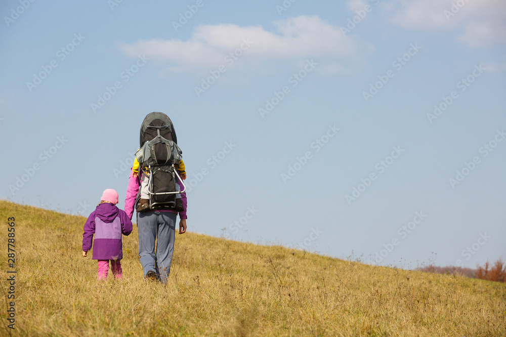 Mother with children hiking on a nice autumn day carrying kid