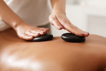 Foto auf Acrylglas Massagesalon Masseur doing back hot stone massage, closeup  © Prostock-studio