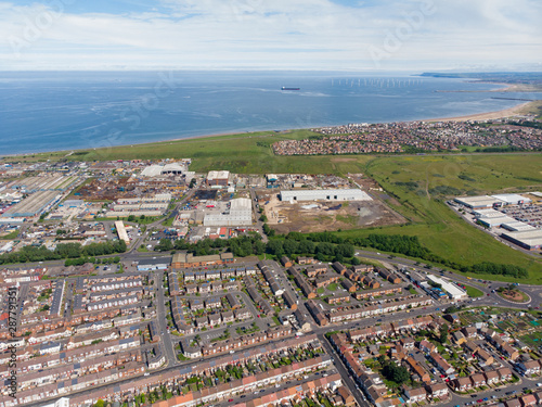Aerial photo of the UK town of Hartlepool in County Durham, England showing rows of houses, roads and the ocean in the background.