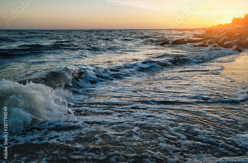Beautiful sunset and sea view. Waves, foam and coastline. Summer.