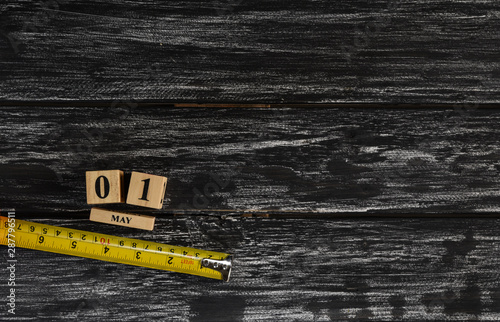 May 1 text wooden block calendar and tape measure on black wooden background for Worker day, Labor day, labour day.