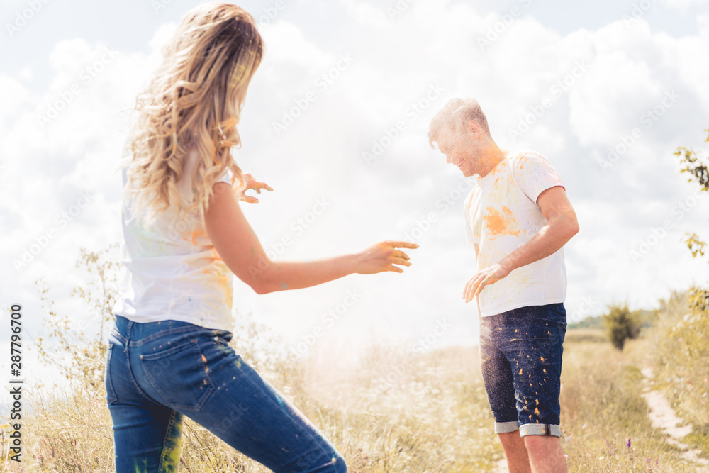 woman and handsome man in t-shirts throwing colorful powder woman and handsome man in t-shirts throwing colorful powder