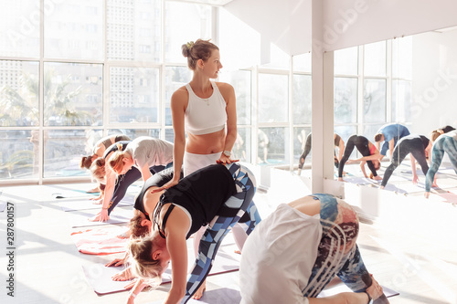 Positive woman yoga instructor rejoices and corrects the movement of their students during group classes in the gym. Yoga concept of meditation and pilates photo