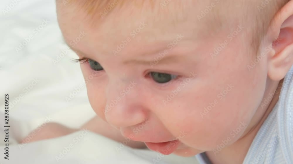 A two month old newborn baby cries loudly with pacifier in mouth. Childs face close up view A two month old newborn baby cries loudly with pacifier in mouth. Childs face close up view