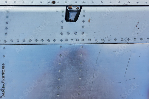 Aluminum surface of the aircraft fuselage. Smooth rows of rivets, there are scratches, dirt