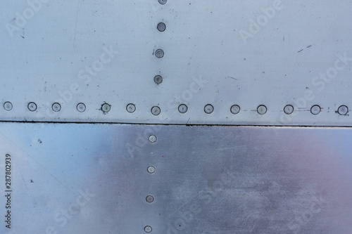 Aluminum surface of the aircraft fuselage. Smooth rows of rivets, there are scratches, dirt