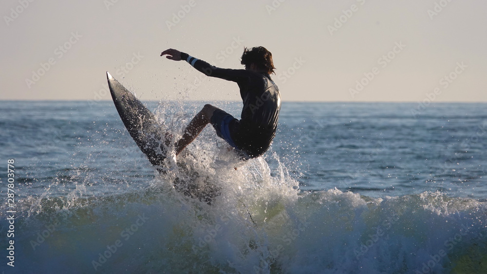 Surfer silhouette jumping wave