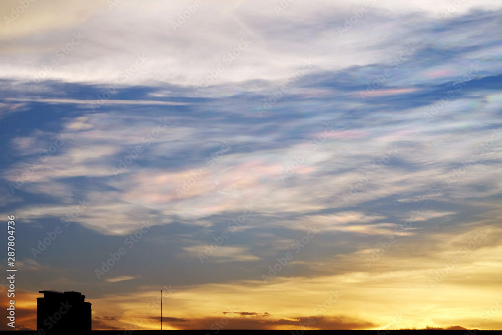 Twilight sky with spectrum reflection on the cloud over the silhouette of building in rural