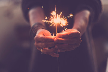 Concept of party nightlife and new year eve 2020 - close up of people hands with red fire sparklers to celebrate the night and the new start - warm colors filter