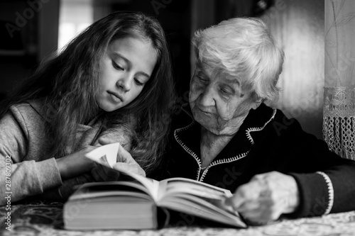A cute little girl with her grandmother reading a book. Black and white photo.