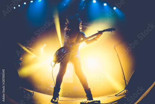 Silhouette of an unrecognizable woman playing the electric guitar