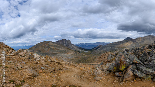 Hiking trail through a panoramic Rocky Mountain landscape with a white clouds  mountains and hills.