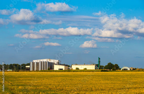 Agricultural Silos. Storage and drying of grains, wheat, corn, soy, sunflower against the blue sky with white clouds.Storage of the crop