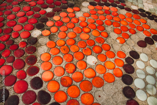 Texture old mosaic made of round orange, red and brown smalt embedded in concrete.