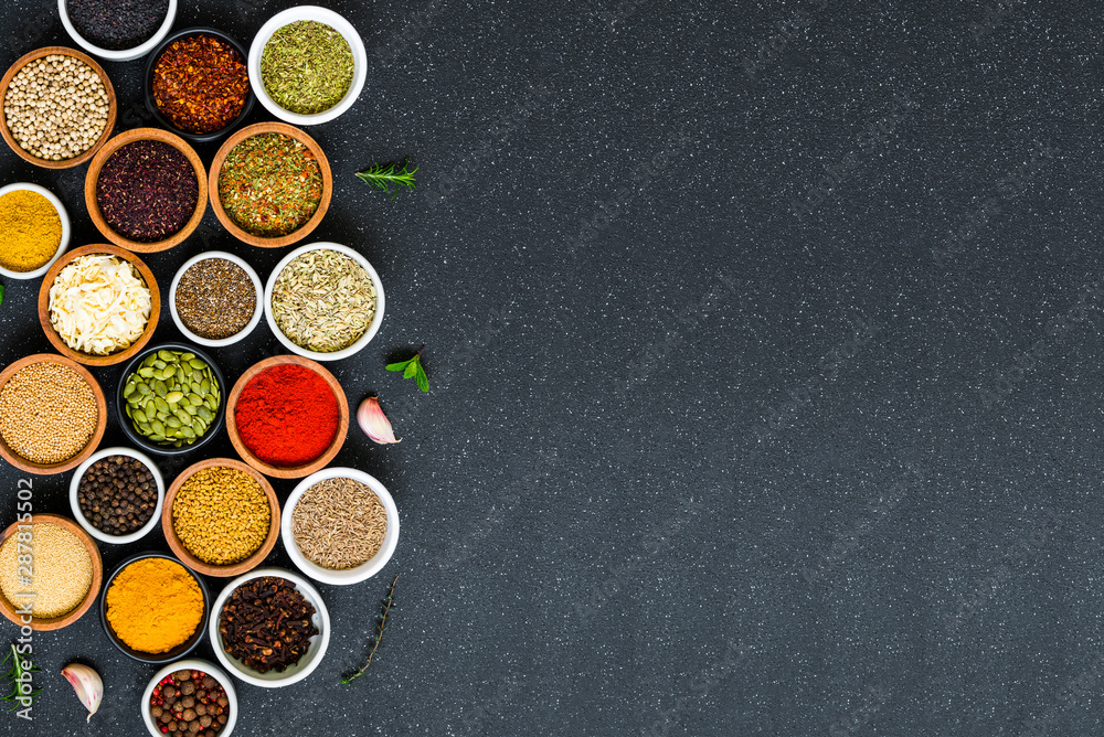 Variety of colorful spices, herbs, and seeds on black stone background Variety of colorful spices, herbs, and seeds on black stone background