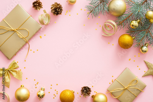 Christmas or New year composition. Christmas presents, ribbon, golden balls, fir tree branches on pastel pink background. Flat lay, top view, overhead
