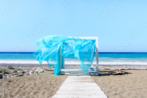 white gazebo with blue fabric on blue ocean background