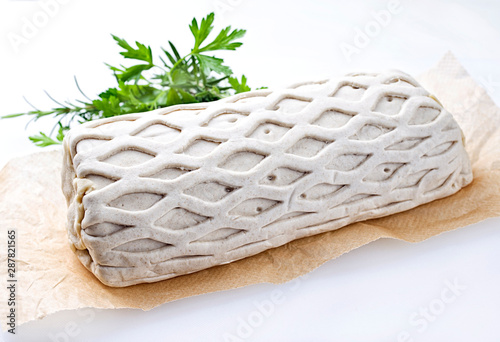 Roher Kasseler Schweinerücken Steak als Stück in Blätterteig Mantel mit Kräuter als closeup angeboten auf Backpapier vor weißen Hintergrund mit Textfreiraum photo