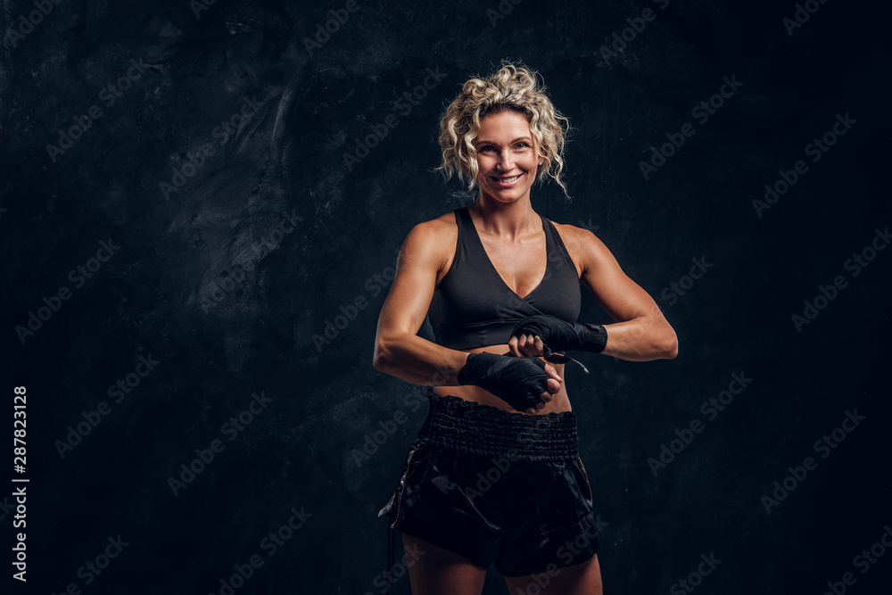 Experienced female boxer is posing for photographer while wearing protective bandages.