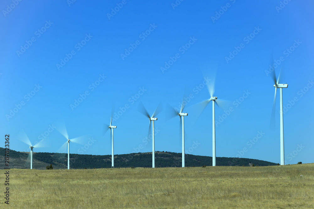 Wind farm, windmills with their blades in motion and the blue sky. Wind and renewable energy Wind farm, windmills with their blades in motion and the blue sky. Wind and renewable energy