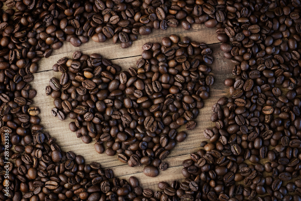 Obraz premium Coffee beans background. Organic coffee. Coffee beans on a wooden background in the form of a heart